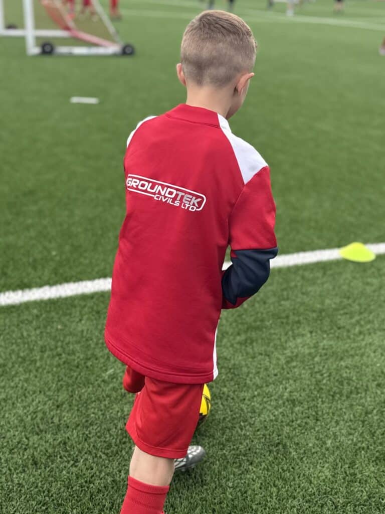 Child in red sportswear with Groundtek Civils Ltd logo, ready for play.