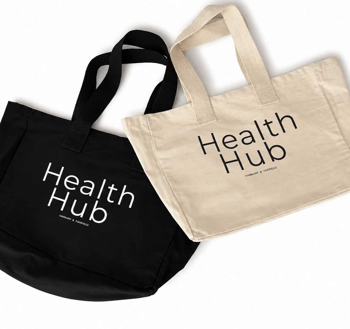 Black and beige tote bags with 'Health Hub' logo for eco-friendly shopping.